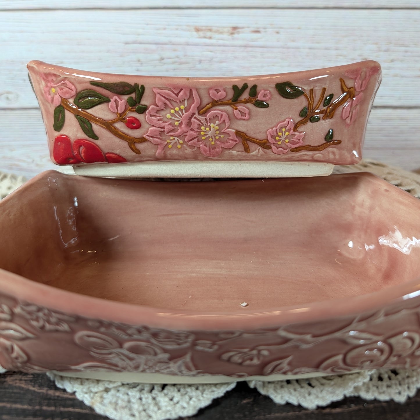 Two pink ceramic dishes with floral design, placed on a white lace doily.