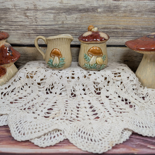 Ceramic mushroom containers with a lace doily on a wooden surface