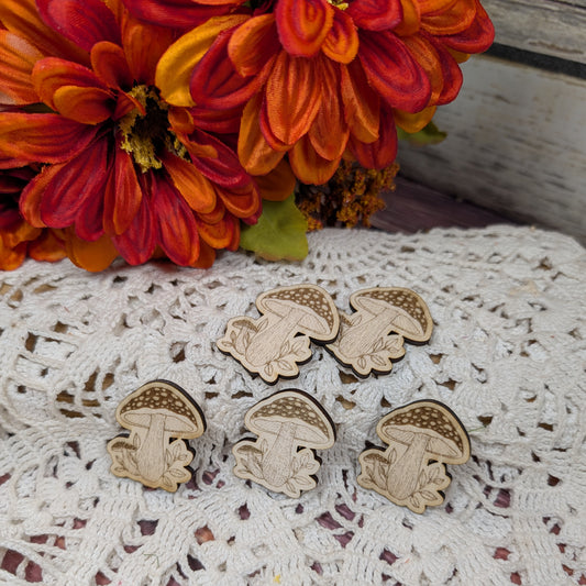 Wooden mushroom magnets on a lace doily with orange flowers in the background