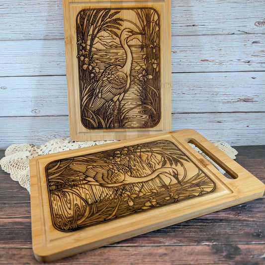 Wooden cutting board with engraved design of a bird and nature scene on a wooden surface.
