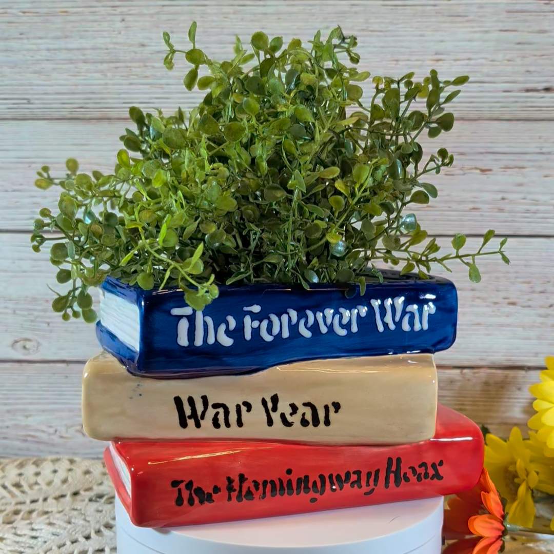 A planter that looks like a stack of books, on a plastic stand, with a wooden background.