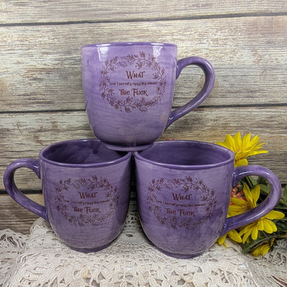 Three purple mugs with text on a wooden surface with flowers.