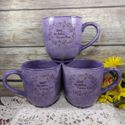 Three purple mugs with text on a wooden surface with flowers.