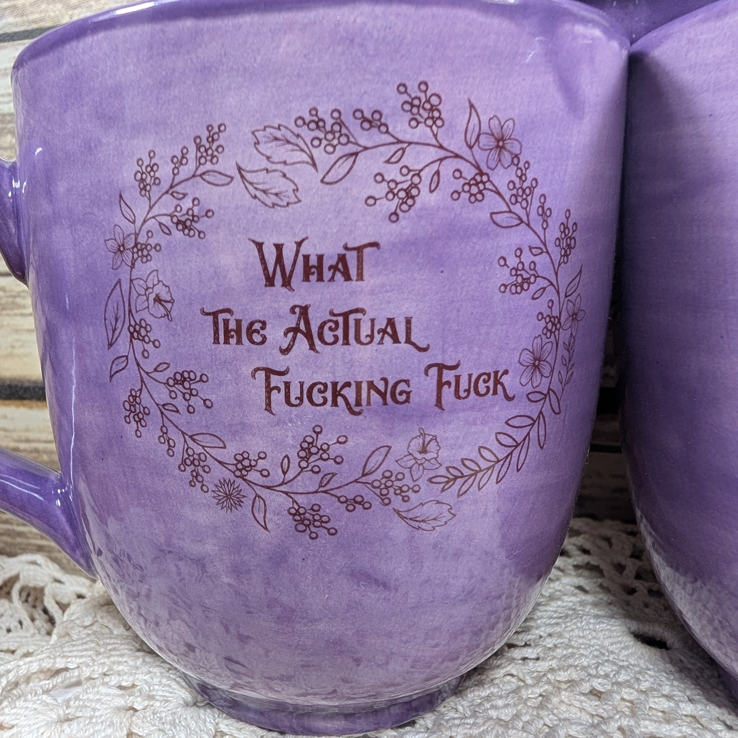 Purple mug with floral design and text on a textured surface