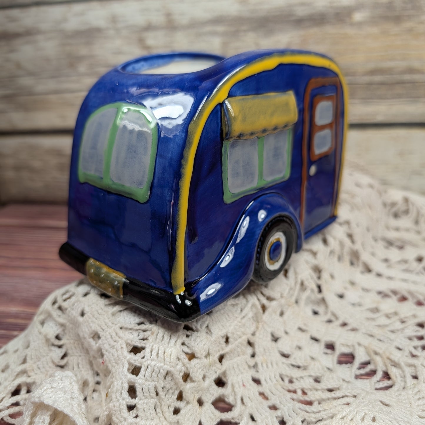 Blue ceramic camper-shaped planter on a textured surface