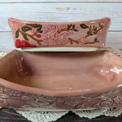 Two pink ceramic dishes with floral design, placed on a white lace doily.