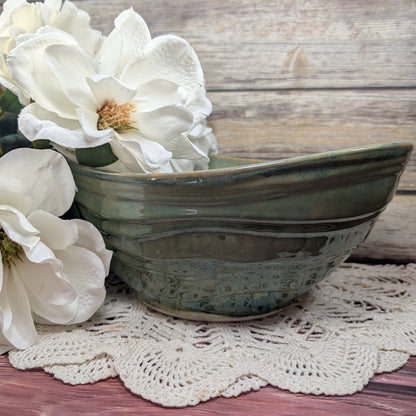 Green ceramic bowl with white flowers on a wooden surface