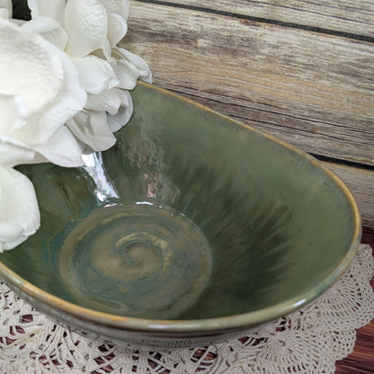 Green ceramic bowl with white flowers on a lace doily