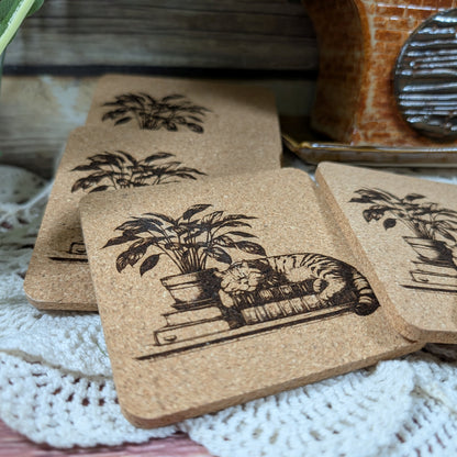 Set of cork coasters with illustrations of a cat and plant on top of books.