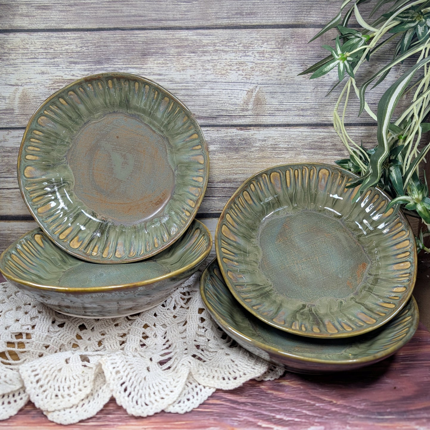 Set of green ceramic bowls on a wooden surface with a plant in the background