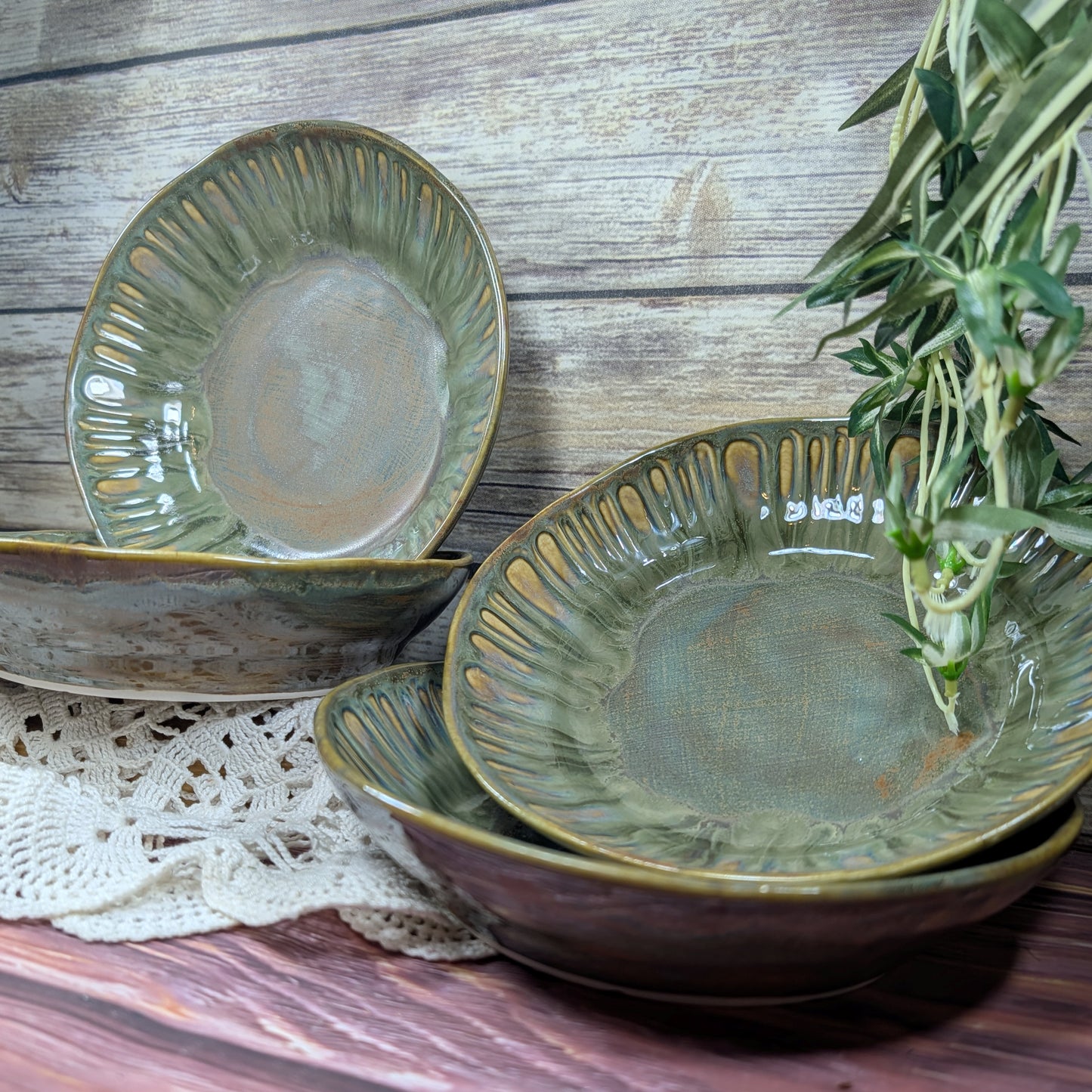 Set of green ceramic bowls on a wooden surface with a sprig of thyme.