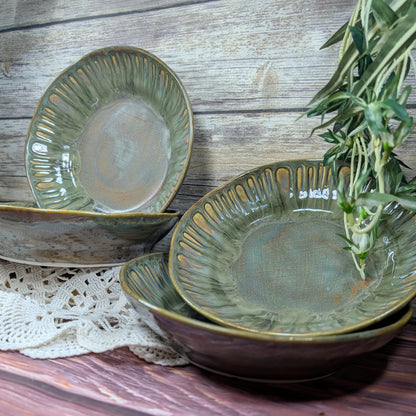 Set of green ceramic bowls on a wooden surface with a sprig of thyme.