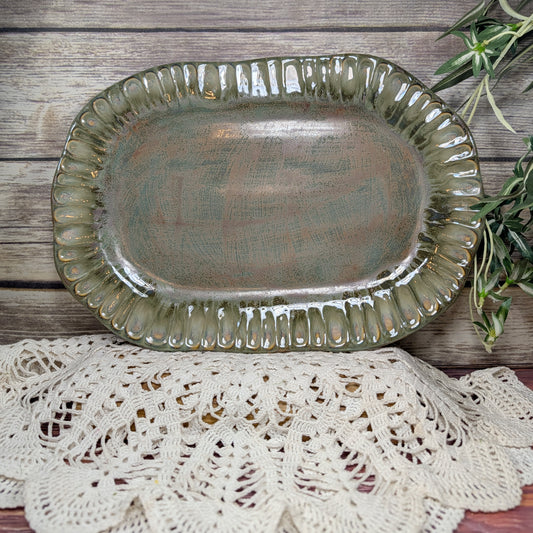 Decorative ceramic platter on a wooden surface with a doily underneath