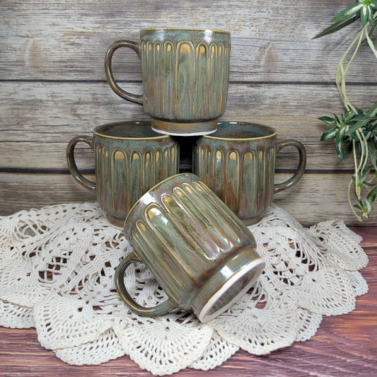 Set of four ceramic mugs with a textured finish on a lace doily.