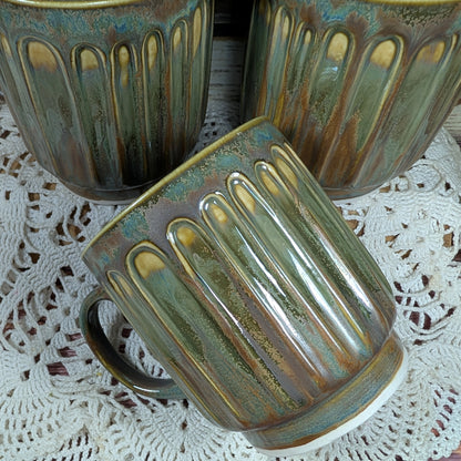Three ceramic mugs with ribbed design on a lace tablecloth