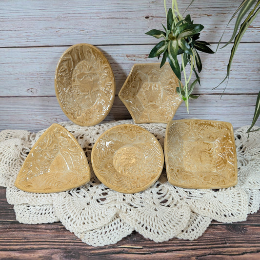 Set of small ceramic trinket dishes, decorated with a mushroom motif, on a lace doily with a wooden background