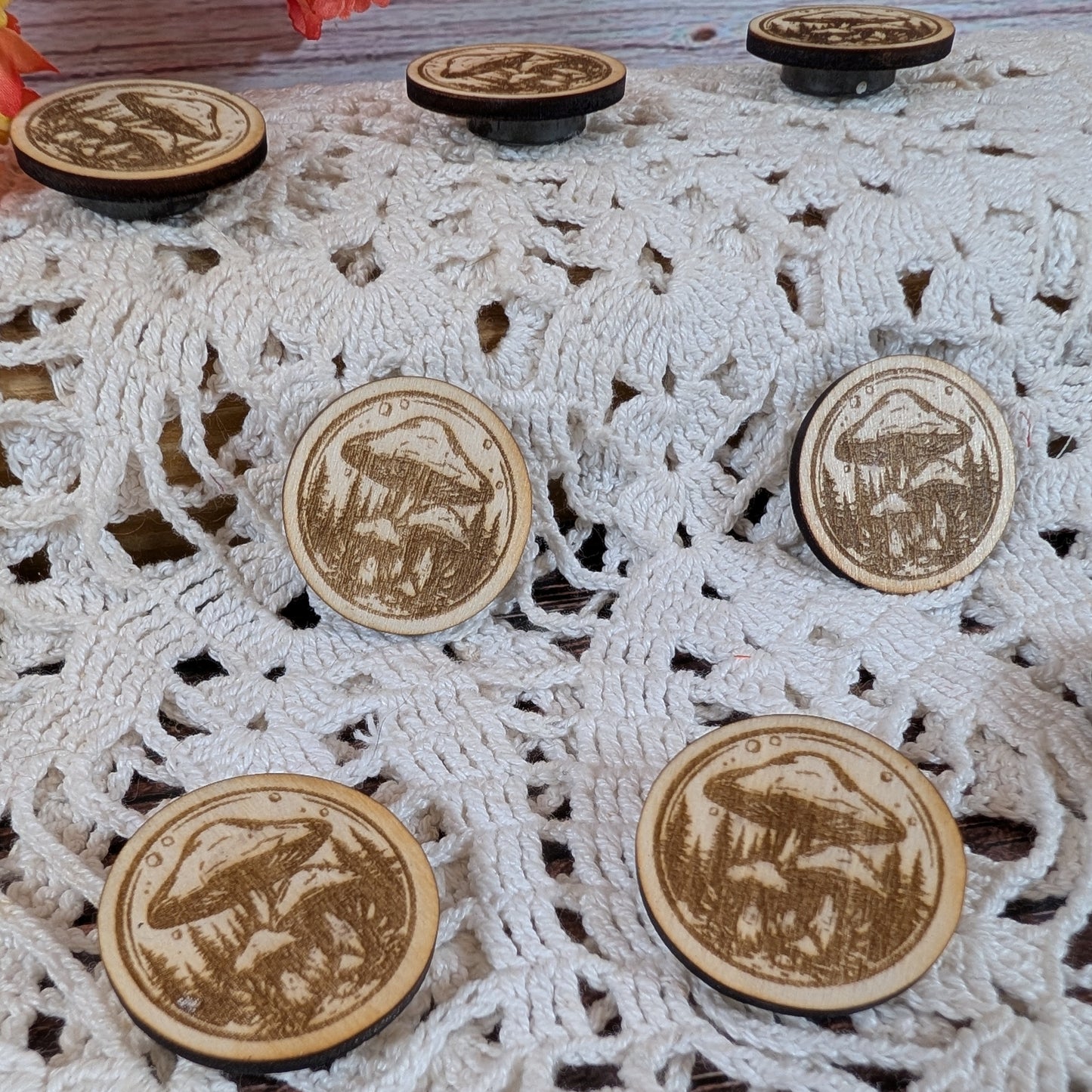 Wooden magnets with engraved mushroom designs on a lace fabric background