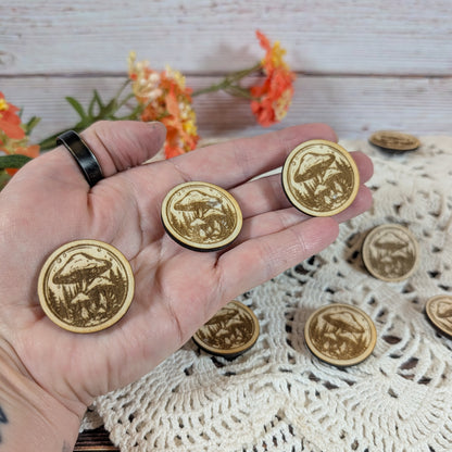 Hand holding round mushroom magnets with flowers in the background