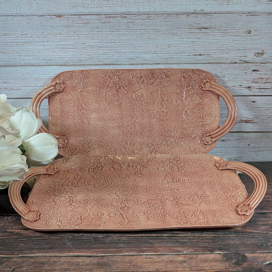 Two long pink trays with floral patterns on a wooden surface