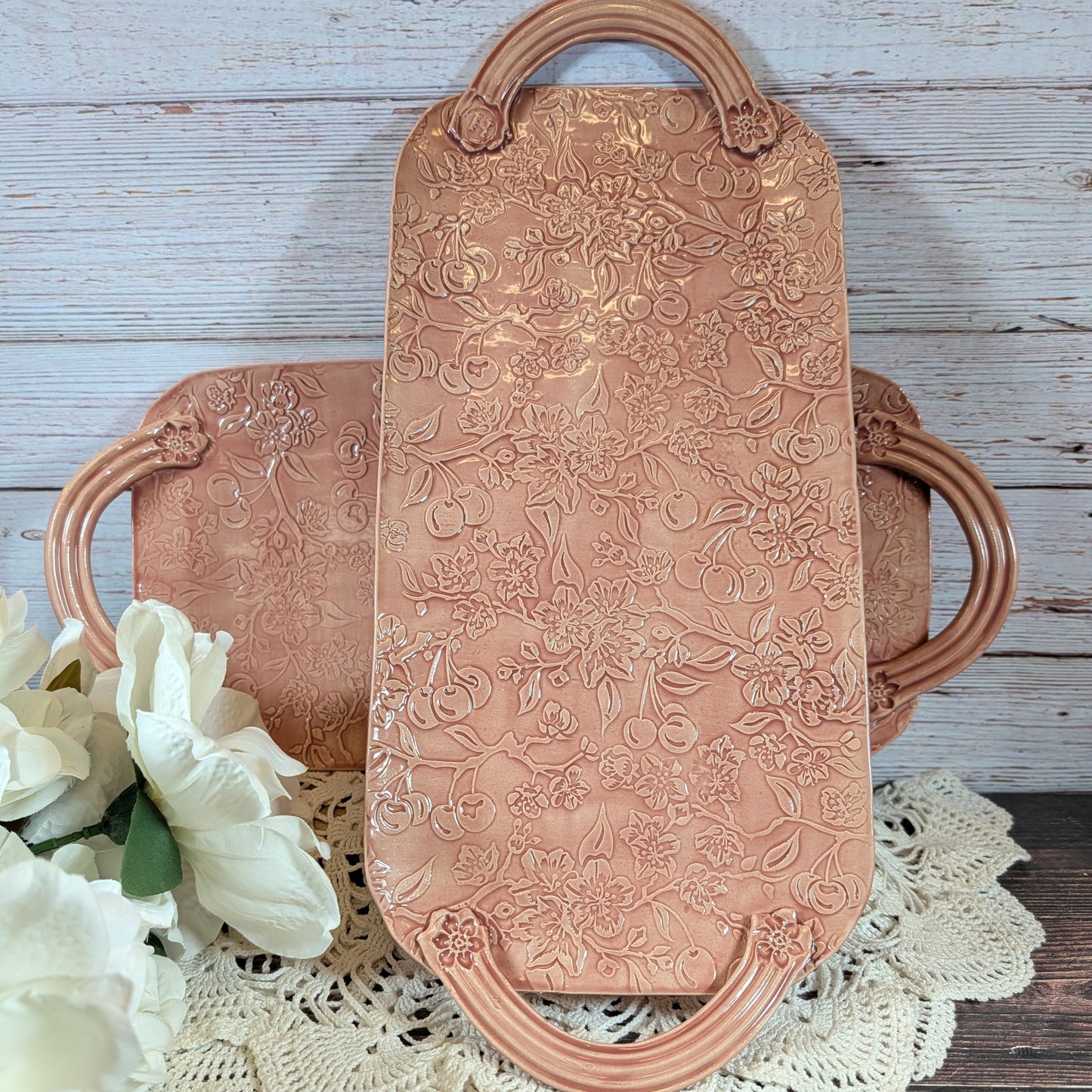 Two long pink trays with floral patterns on a wooden surface