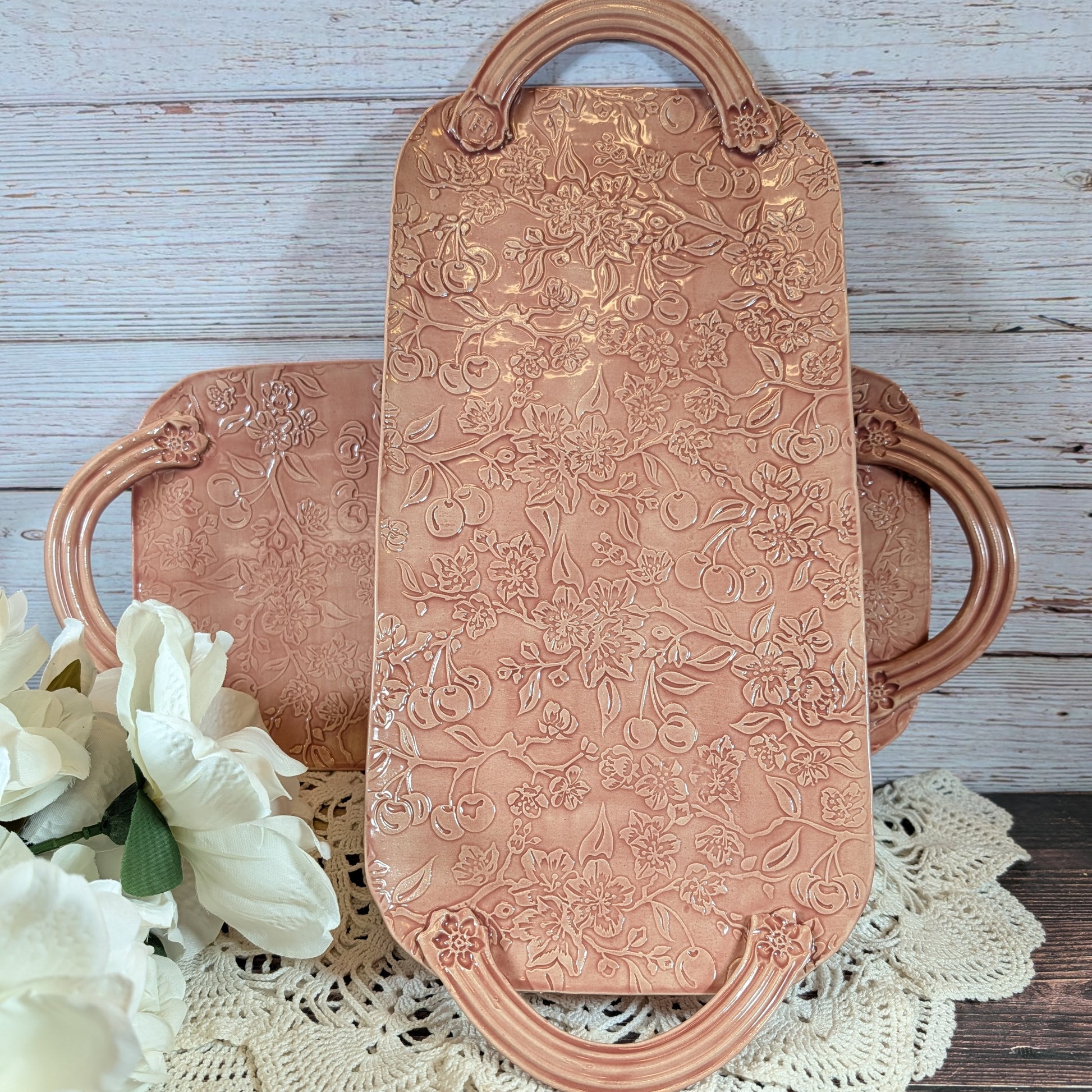 Two long pink trays with floral patterns on a wooden surface