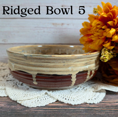 Ridged ceramic bowl with brown and beige patterns on a wooden surface with flowers.