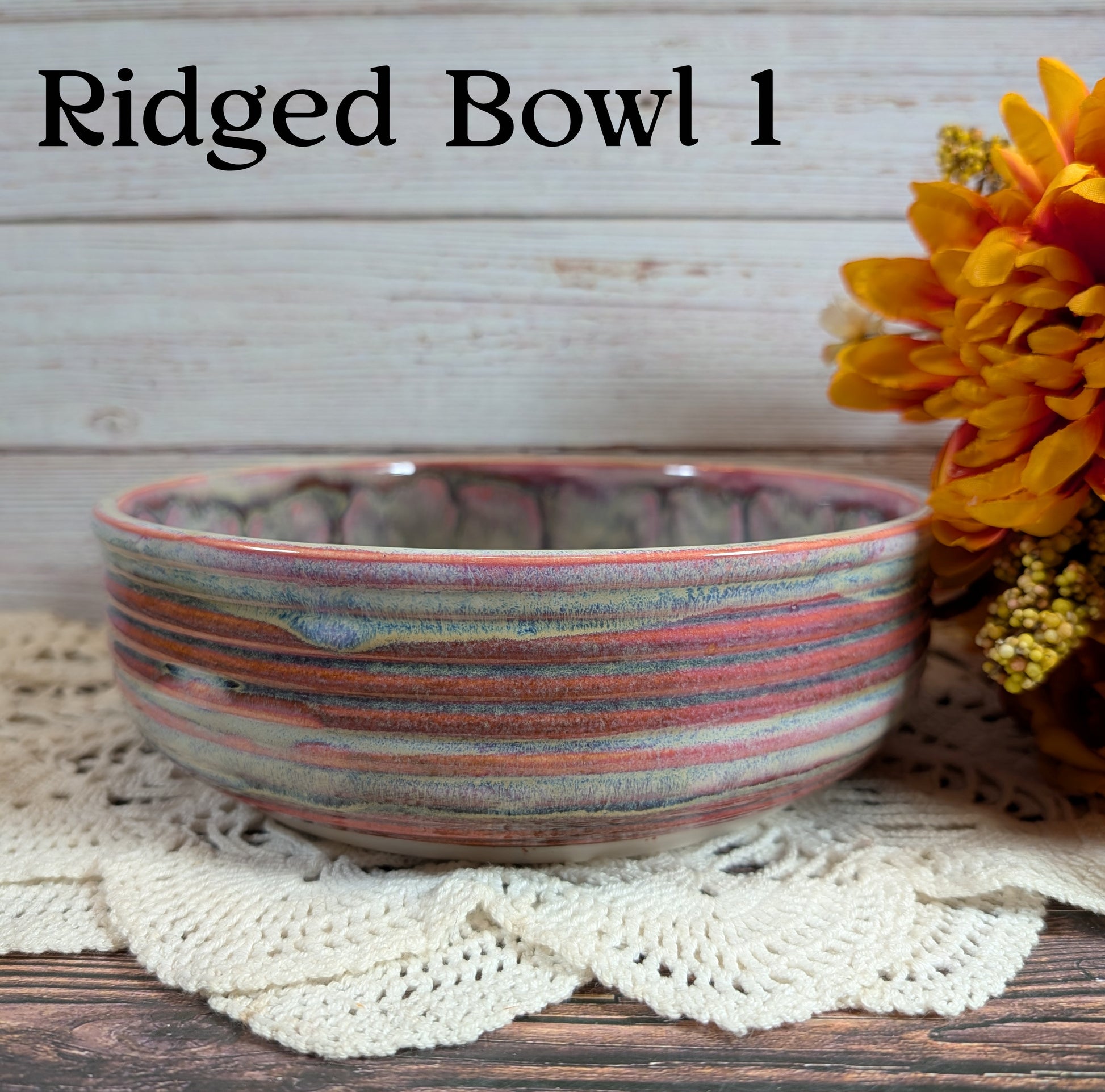 Ridged ceramic bowl with a pink and gray striped pattern on a wooden surface with flowers.