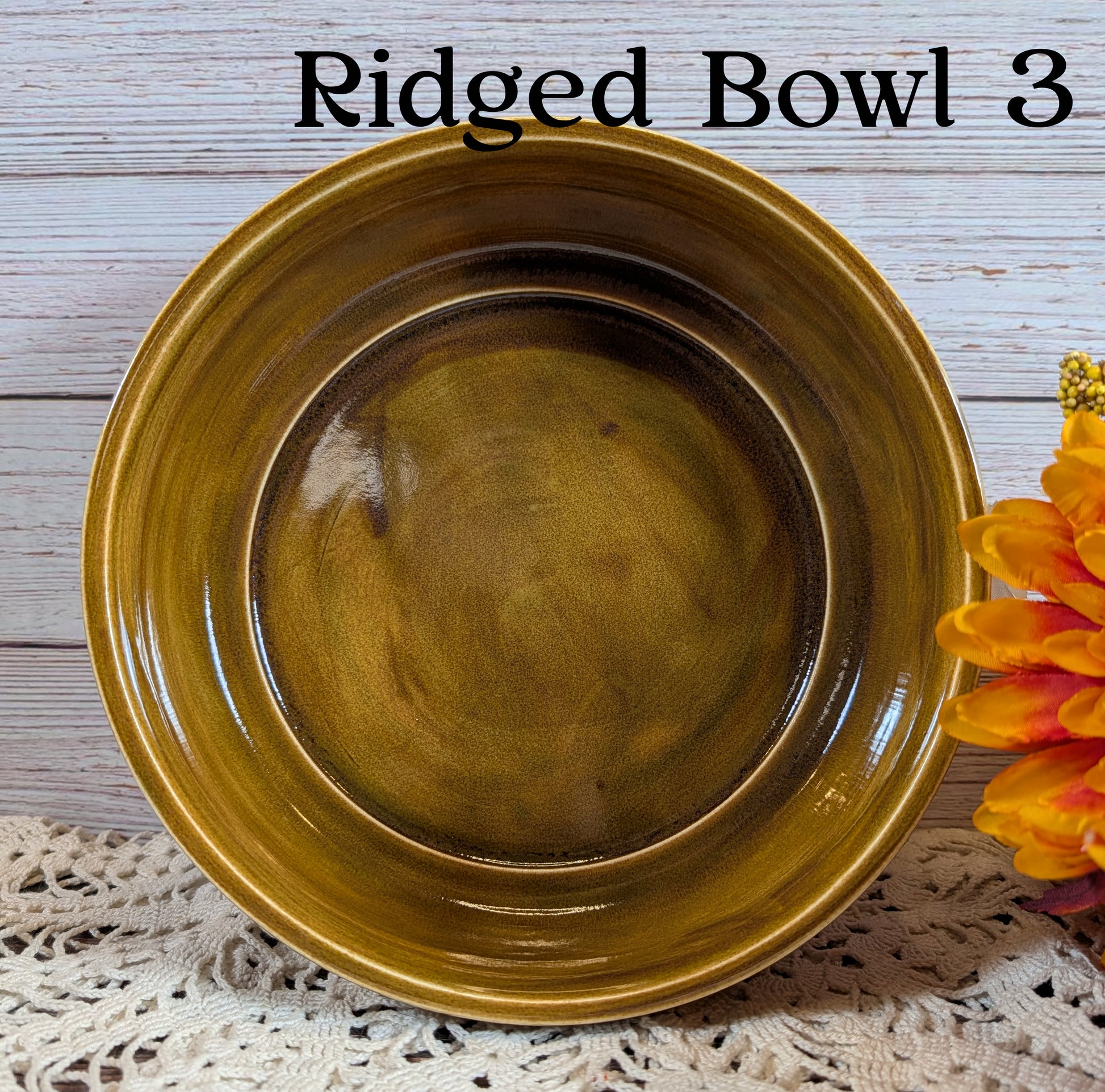 Brown ridged bowl on a textured surface with a flower in the corner