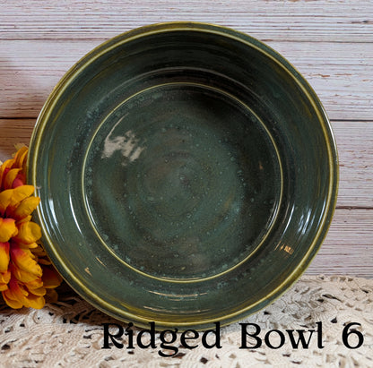 Green ridged bowl labeled 'Ridged Bowl 6' on a wooden surface with flowers.
