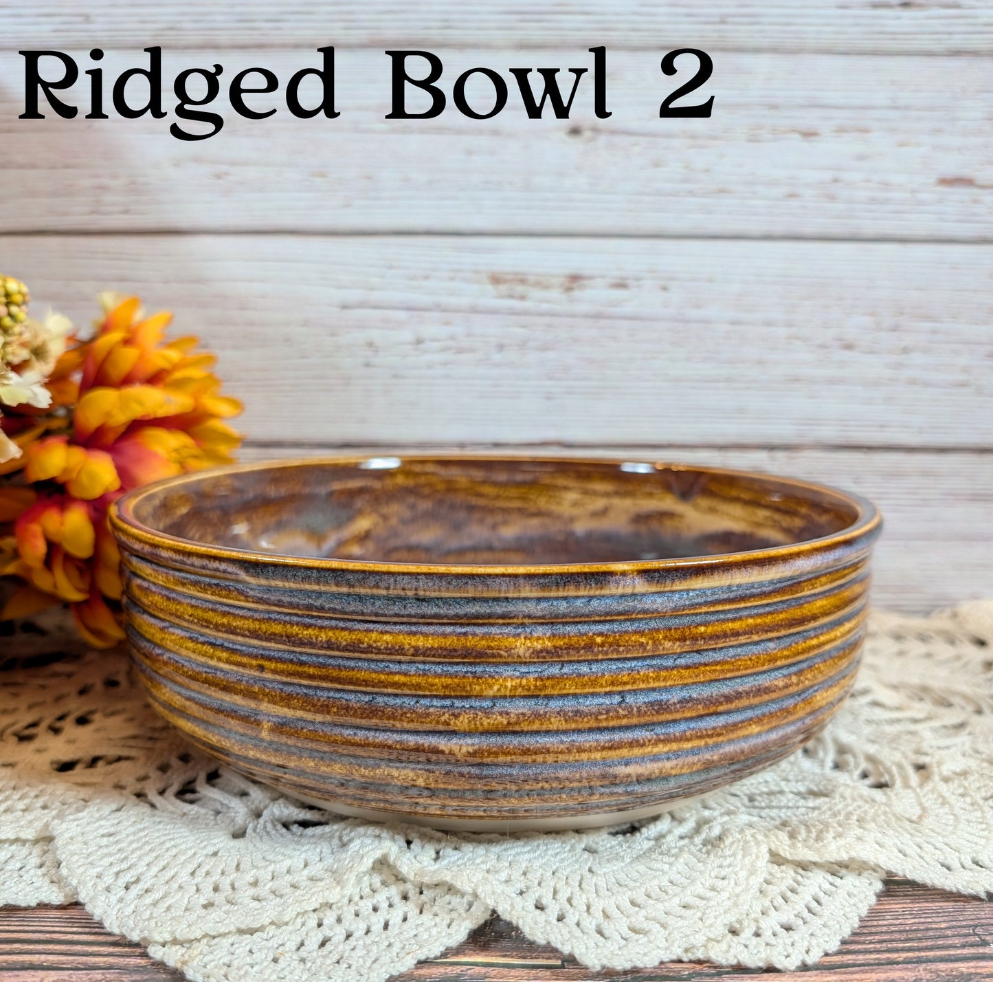 Ridged ceramic bowl with brown and gray glaze on a textured surface with flowers.