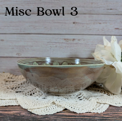 Brown and gray ceramic bowl on a doily with a white flower, against a wooden background.