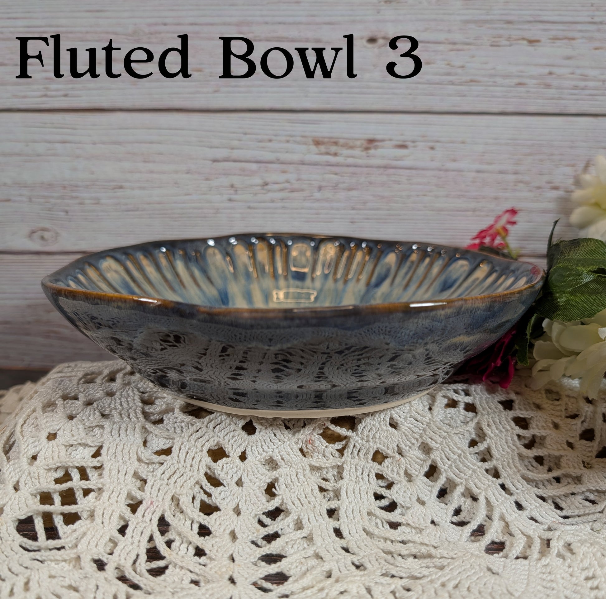 Fluted bowl labeled 'Fluted Bowl 3' on a textured surface with a floral arrangement.