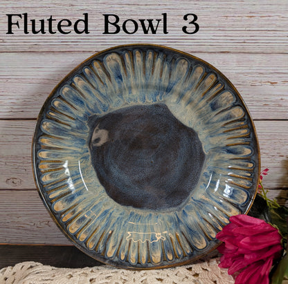 A dark blue and gray ceramic bowl with decorative edge on a wooden surface