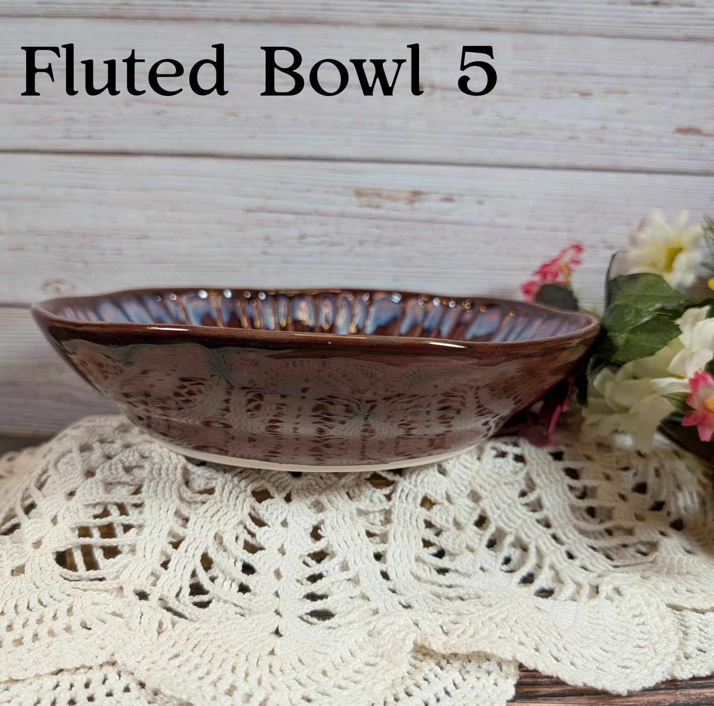 Red bowl on a lace tablecloth with flowers in the background