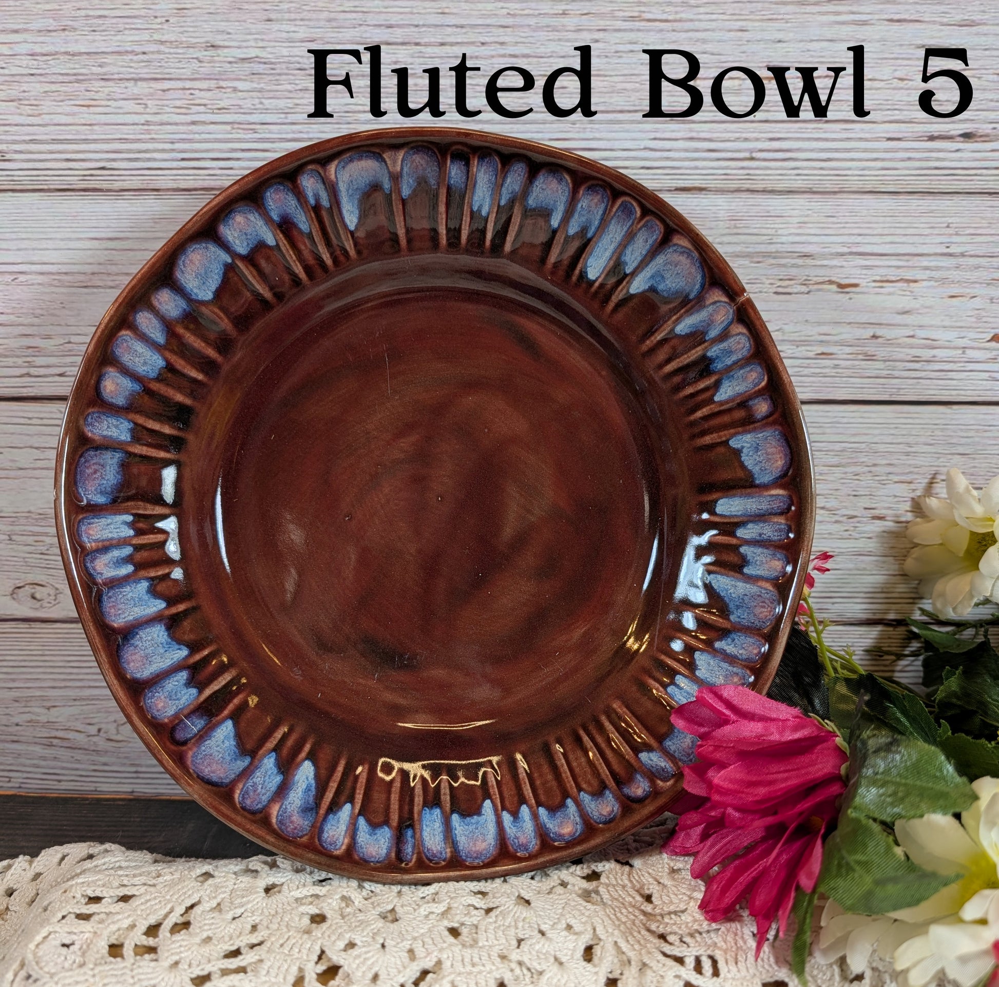 Fluted bowl with decorative edge on a wooden surface with flowers.