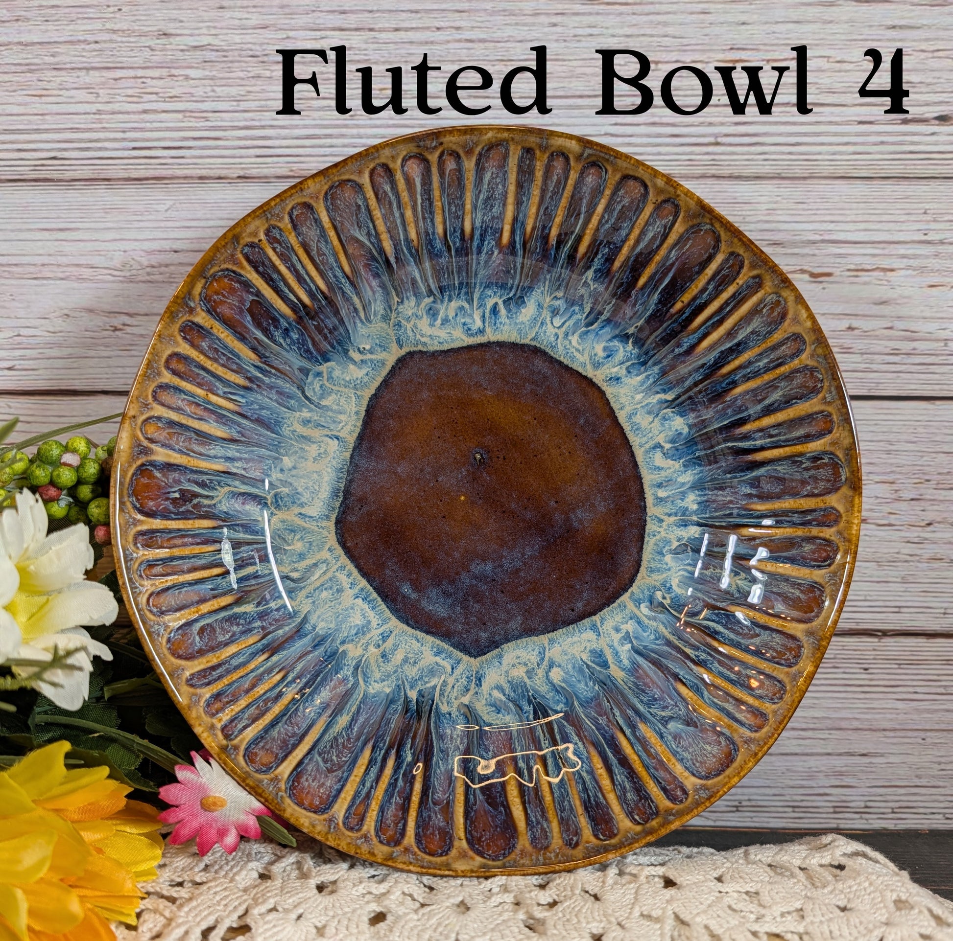 Brown and gold bowl with decorative patterns on a wooden surface with flowers.