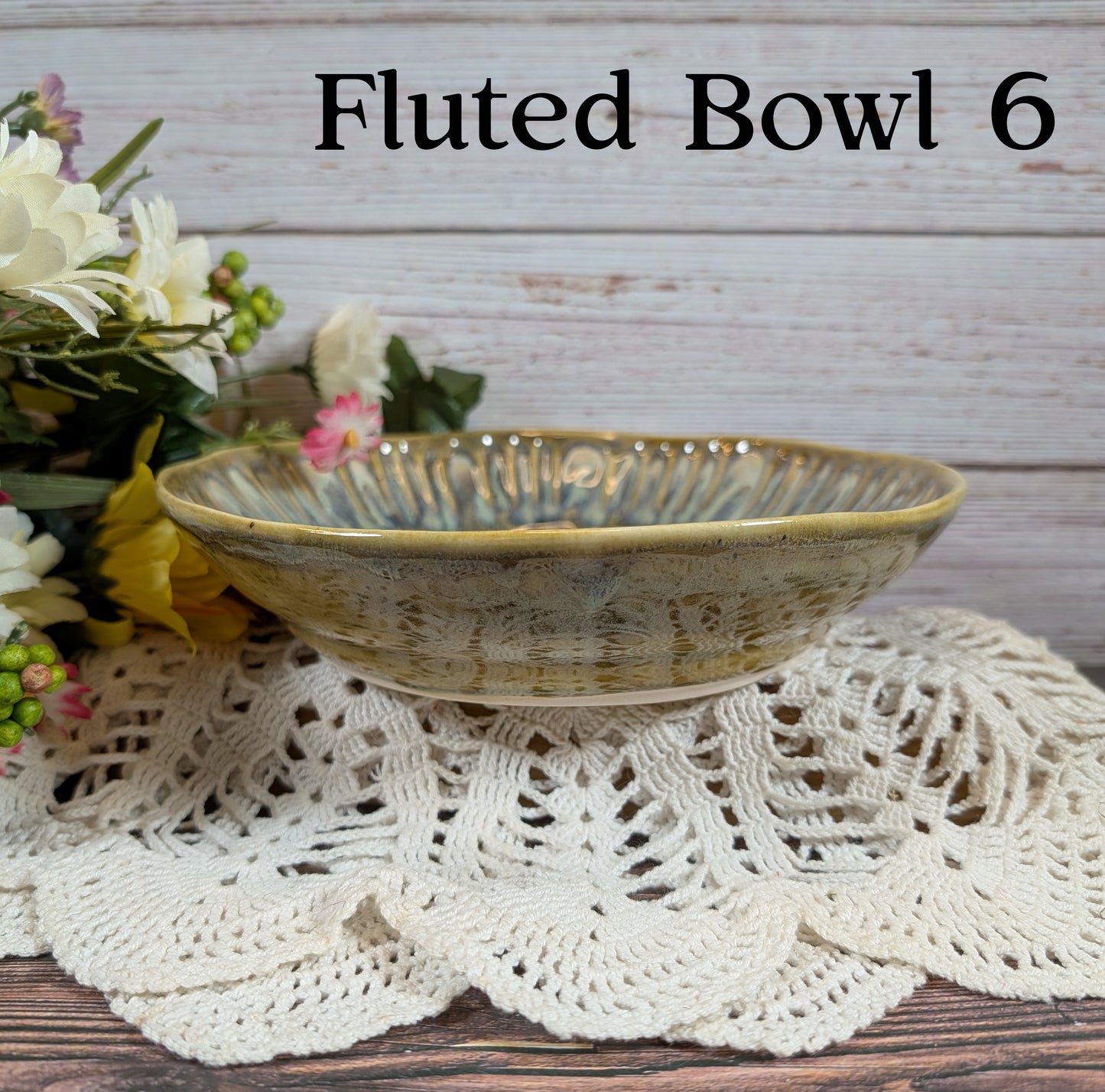 Green bowl on a lace doily with flowers in the background