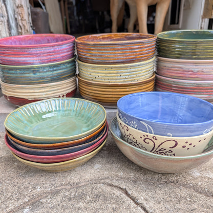 Stacks of colorful ceramic bowls on a concrete surface