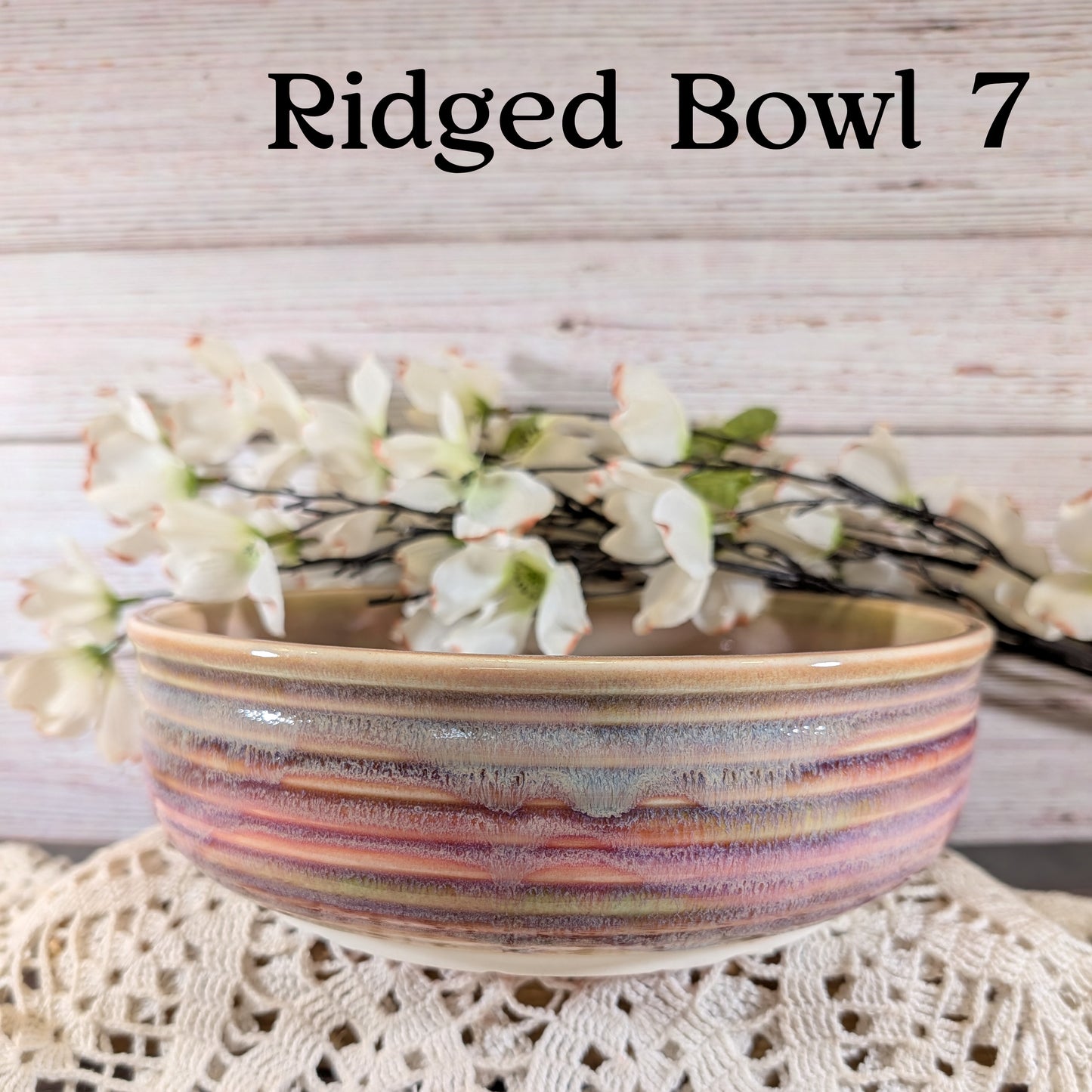 Pink, gray, and yellow ceramic bowl with floral arrangement on a textured surface
