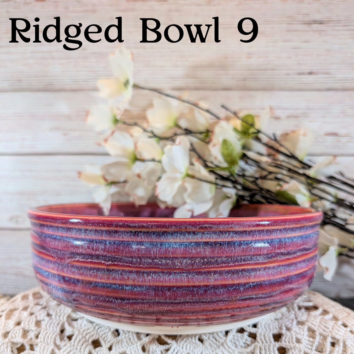 Ridged bowl with purple and red stripes on a lace tablecloth with flowers in the background