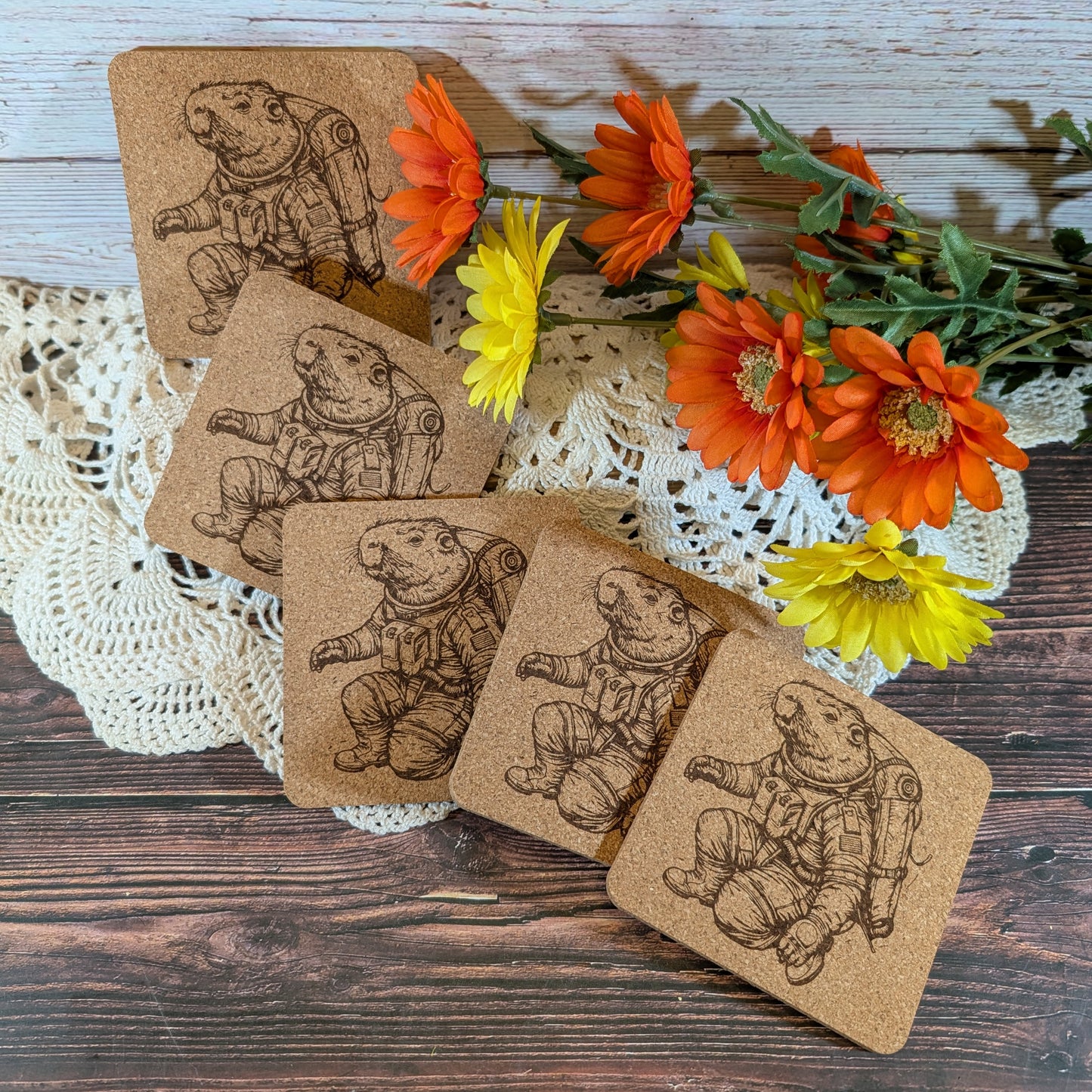Cork coasters with astronaut design on a wooden surface with flowers.