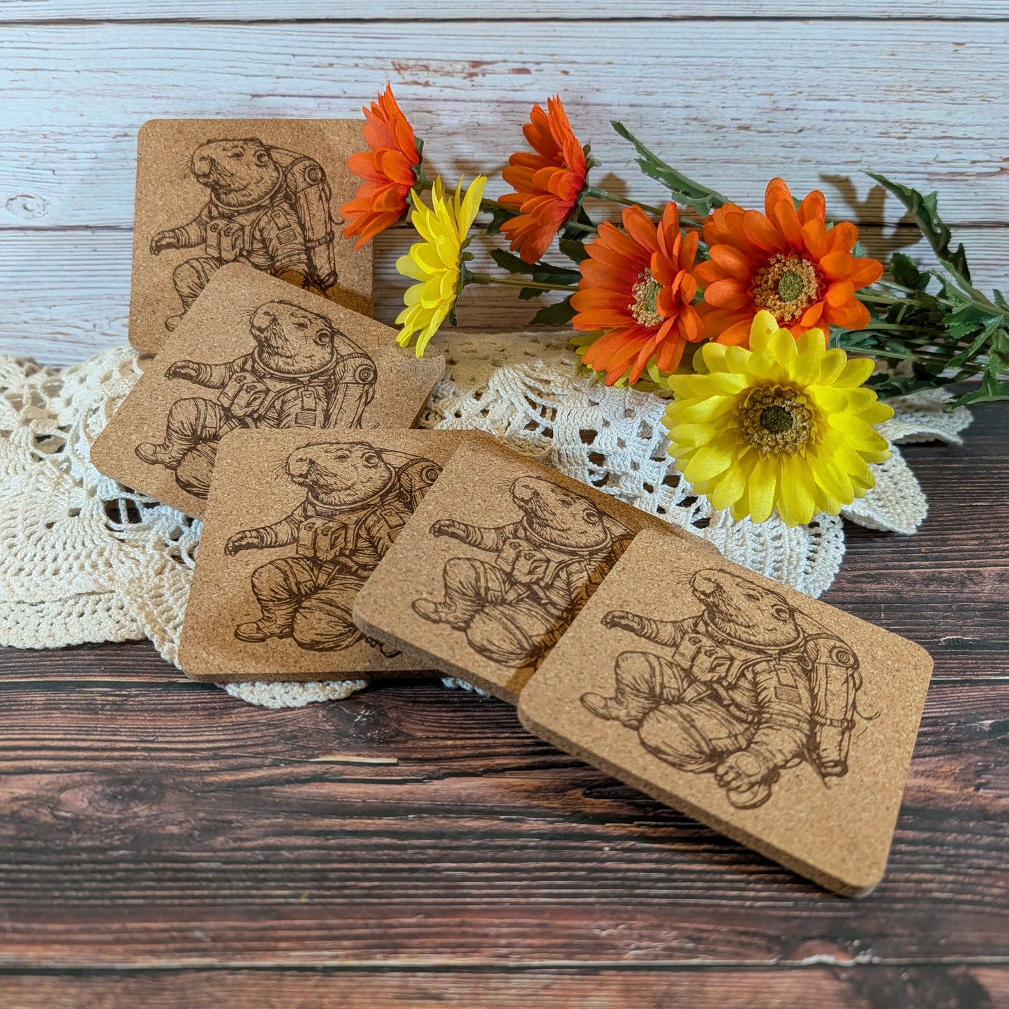 Set of cork coasters with engraved illustrations on a wooden surface with flowers.
