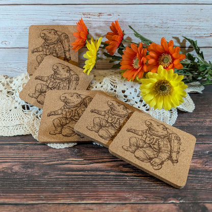 Set of cork coasters with engraved illustrations on a wooden surface with flowers.