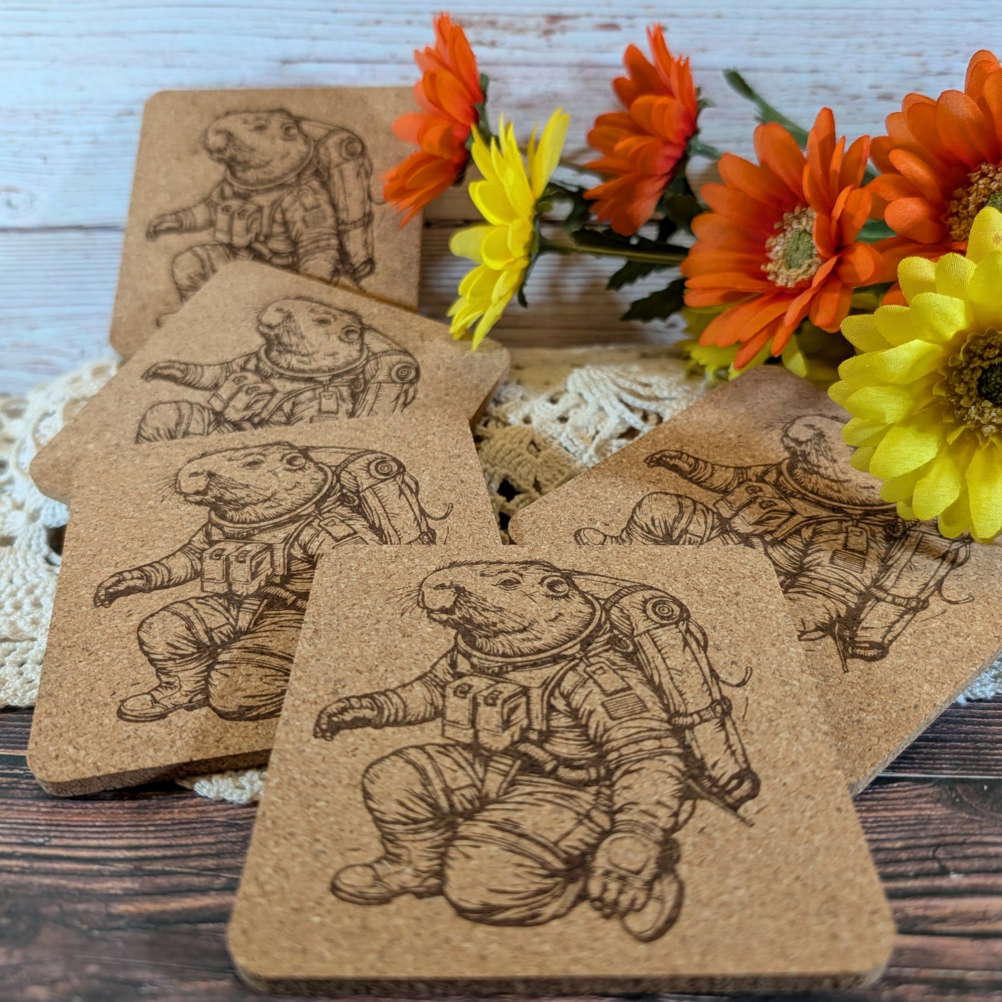 Cork coasters with astronaut design on a wooden surface with flowers in the background