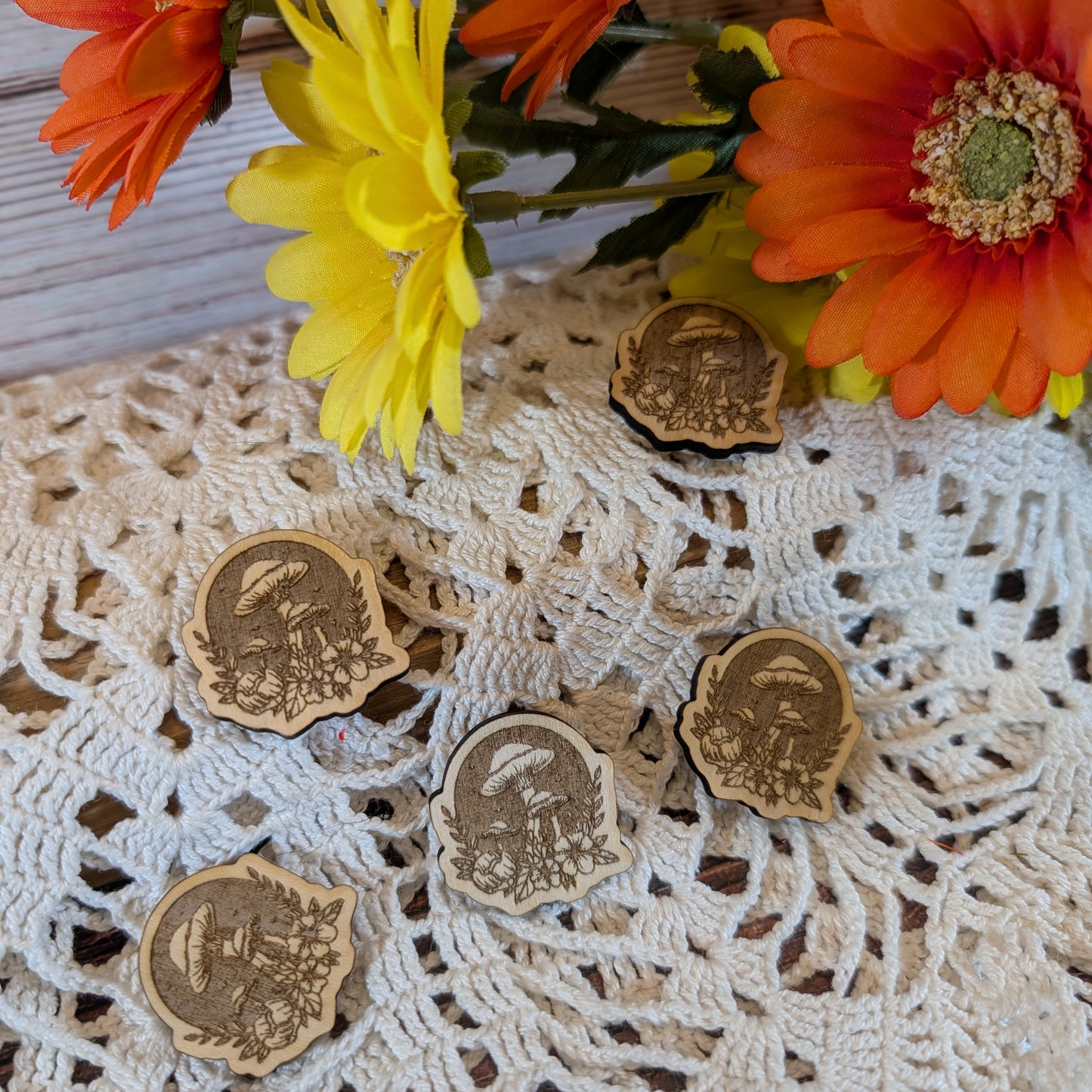 Wooden magnets with floral design on a lace tablecloth with flowers in the background